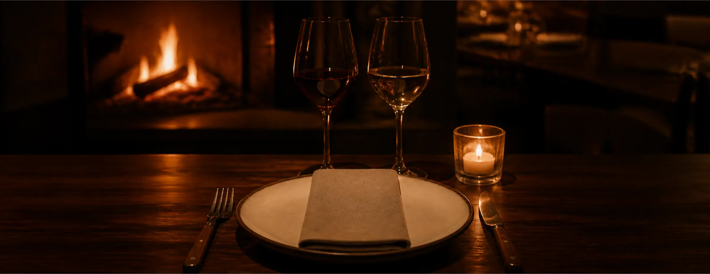 A candle-lit table set with linen, silver and polished glassware